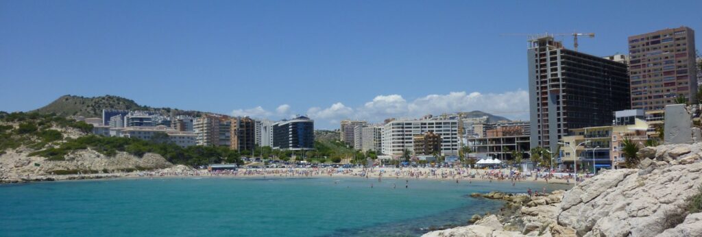 Pláž -  zátoka Cala de Finestrat, která leží na rozhraní měst Villajoyosa a Benidorm. V dálce park v Villajoyosa